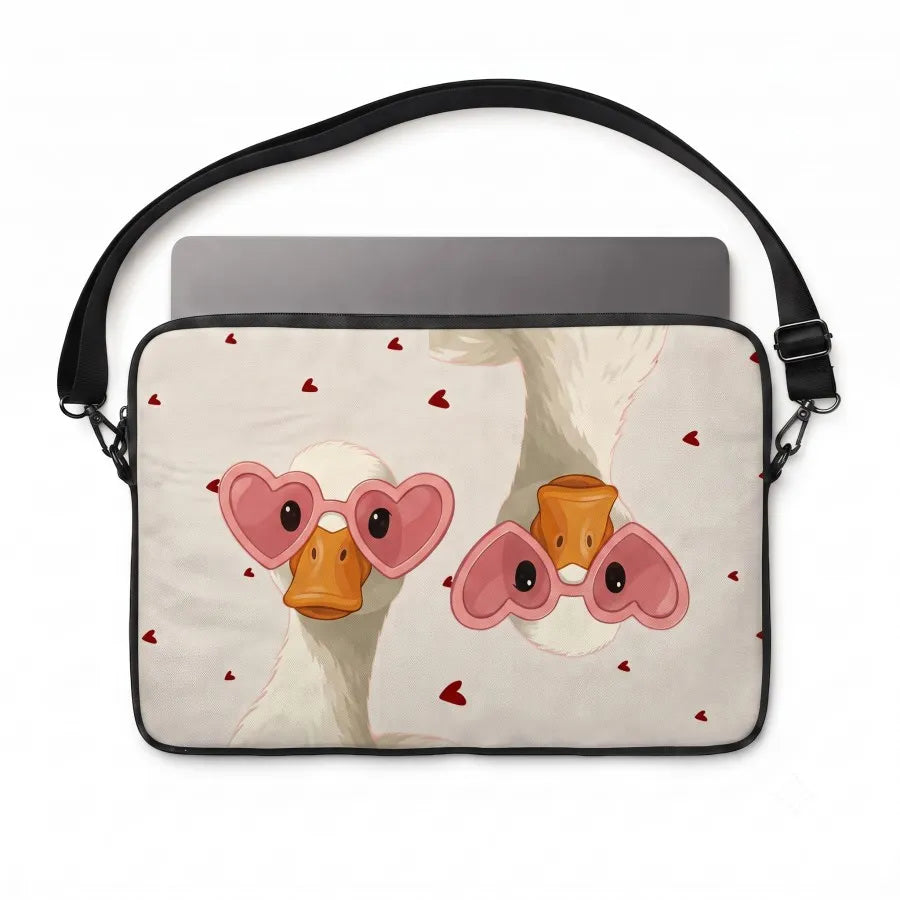 A laptop sleeve featuring a cute cartoon illustration of two white ducks wearing pink heart-shaped sunglasses, with small red hearts scattered on a light beige background. The sleeve has a black strap and is shown with a gray laptop inserted, against a plain white background.