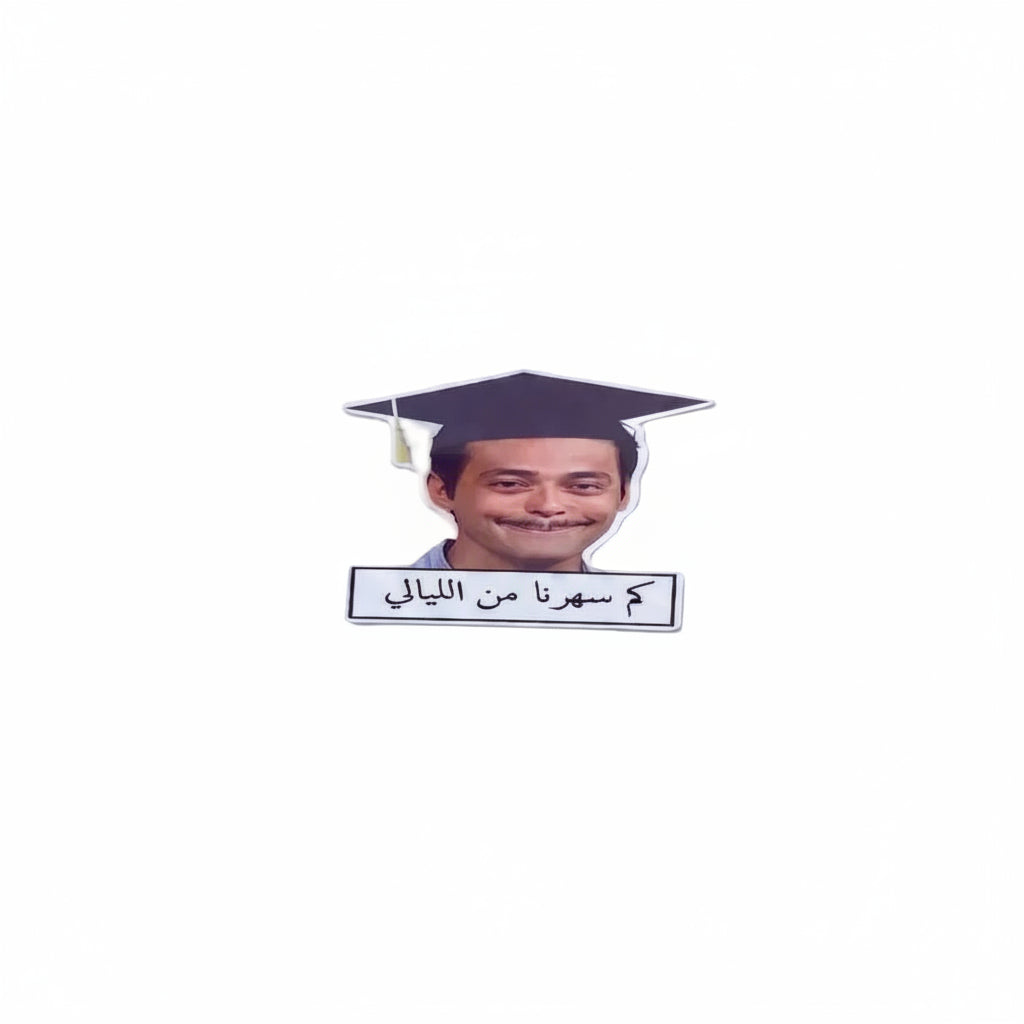 A novelty sticker featuring a cutout of a smiling man wearing a graduation cap with Arabic text below it, displayed on a plain white background.