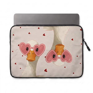A laptop sleeve featuring a cute cartoon illustration of two white ducks wearing pink heart-shaped glasses, with small red hearts scattered on a light beige background. The sleeve has a black zipper border and is shown with a gray laptop partially inserted, on a plain white background.