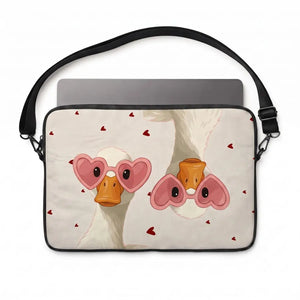 A laptop sleeve featuring a cute cartoon illustration of two white ducks wearing pink heart-shaped sunglasses, with small red hearts scattered on a light beige background. The sleeve has a black strap and is shown with a gray laptop inserted, against a plain white background.