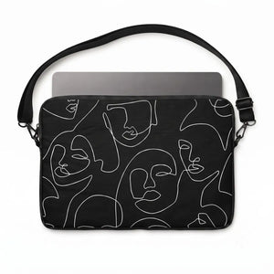 A black laptop sleeve featuring a minimalist white continuous line art pattern of faces, shown with a gray laptop inside on a white background.